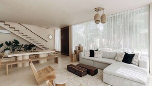 A modern living room with a staircase, a sofa, a coffee table, and a dining area. - Casa Mazuri Jungle Villa Beach Club Access (Tulum)