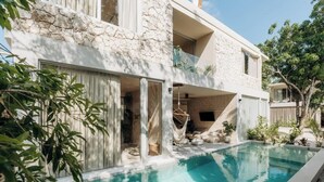 A modern house with a swimming pool, stone exterior, and a balcony with plants. - Casa Mazuri Jungle Villa Beach Club Access (Tulum)
