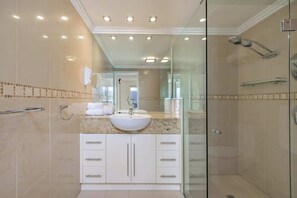 Un bagno moderno con box doccia in vetro, lavandino bianco e mobile contenitore con cassetti.