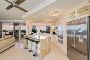 Una cucina moderna con una grande isola, elettrodomestici in acciaio inossidabile e una ventola a soffitto.