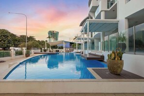 Un hotel moderno con piscina, area salotto esterna e vista sulla città.