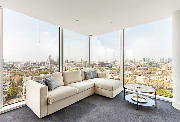 Relax in a spacious living room with a large sofa, coffee table, and stunning city views.