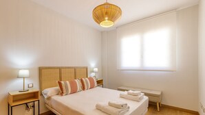 Ein Hotelzimmer mit einem großen Bett, zwei Nachttischen mit Lampen, einer Bank am Fußende des Bettes und einem Fenster mit Jalousien.