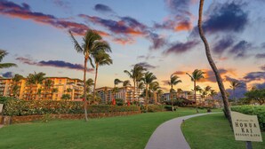 Ein Resort mit einem Weg, Palmen und einem Schild, das herzlich zum Honolulu Kai Resort & Spa einlädt.