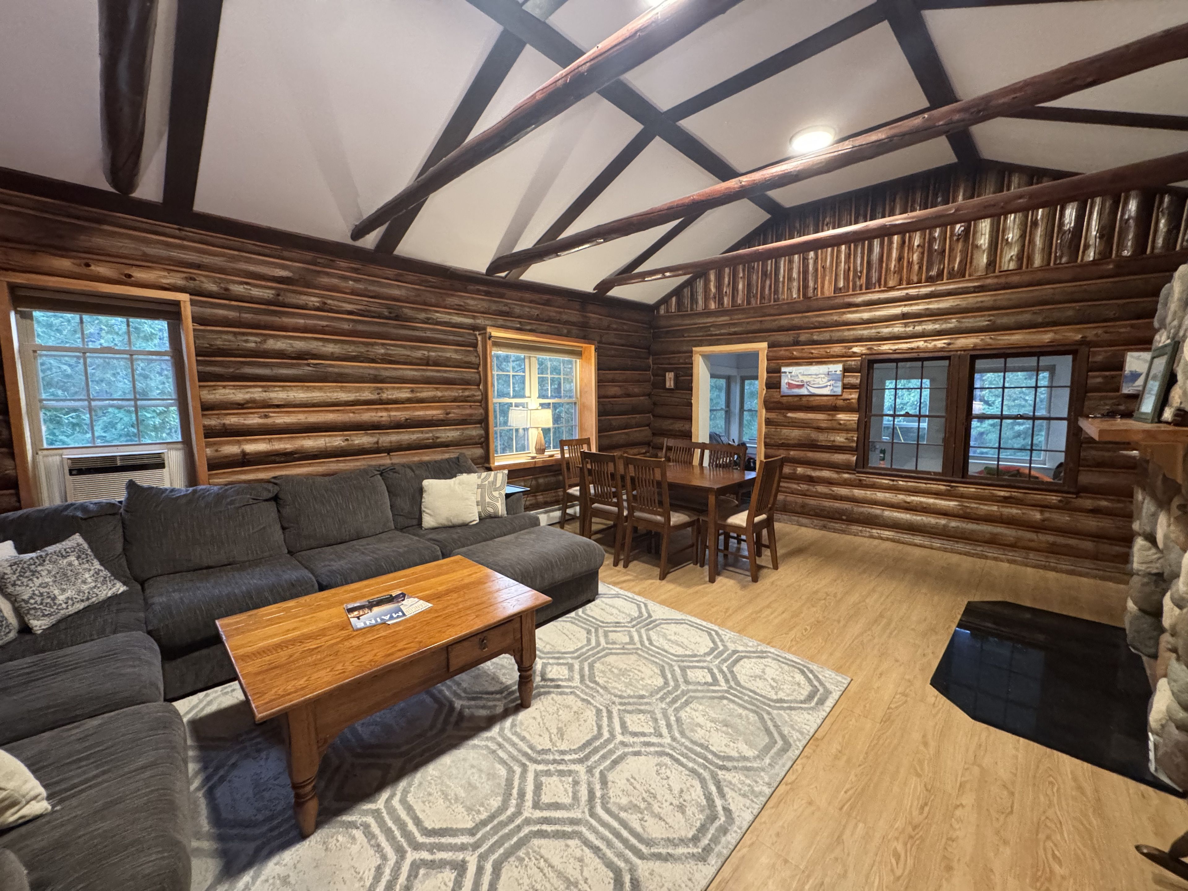 L’intérieur d’une cabane en rondins, avec un canapé, une table à manger et des chaises.