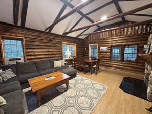 L’intérieur d’une cabane en rondins, avec un canapé, une table à manger et des chaises.