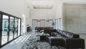 A modern living room with a sectional sofa, a coffee table, and a dining area with a bar. - Casa Samaria (Valle de Guadalupe)