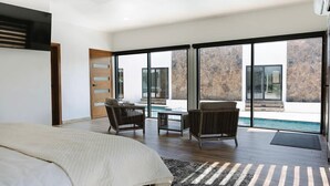 A modern bedroom with a large bed, a view of a swimming pool, and a sliding glass door leading to an outdoor area. - Casa Samaria (Valle de Guadalupe)