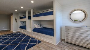 Un dormitorio con literas, un aparador de madera y un espejo en la pared.