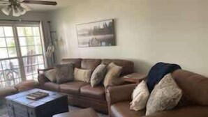 Un salon avec un ensemble de canapés en cuir marron, une table basse et un tableau accroché au mur.