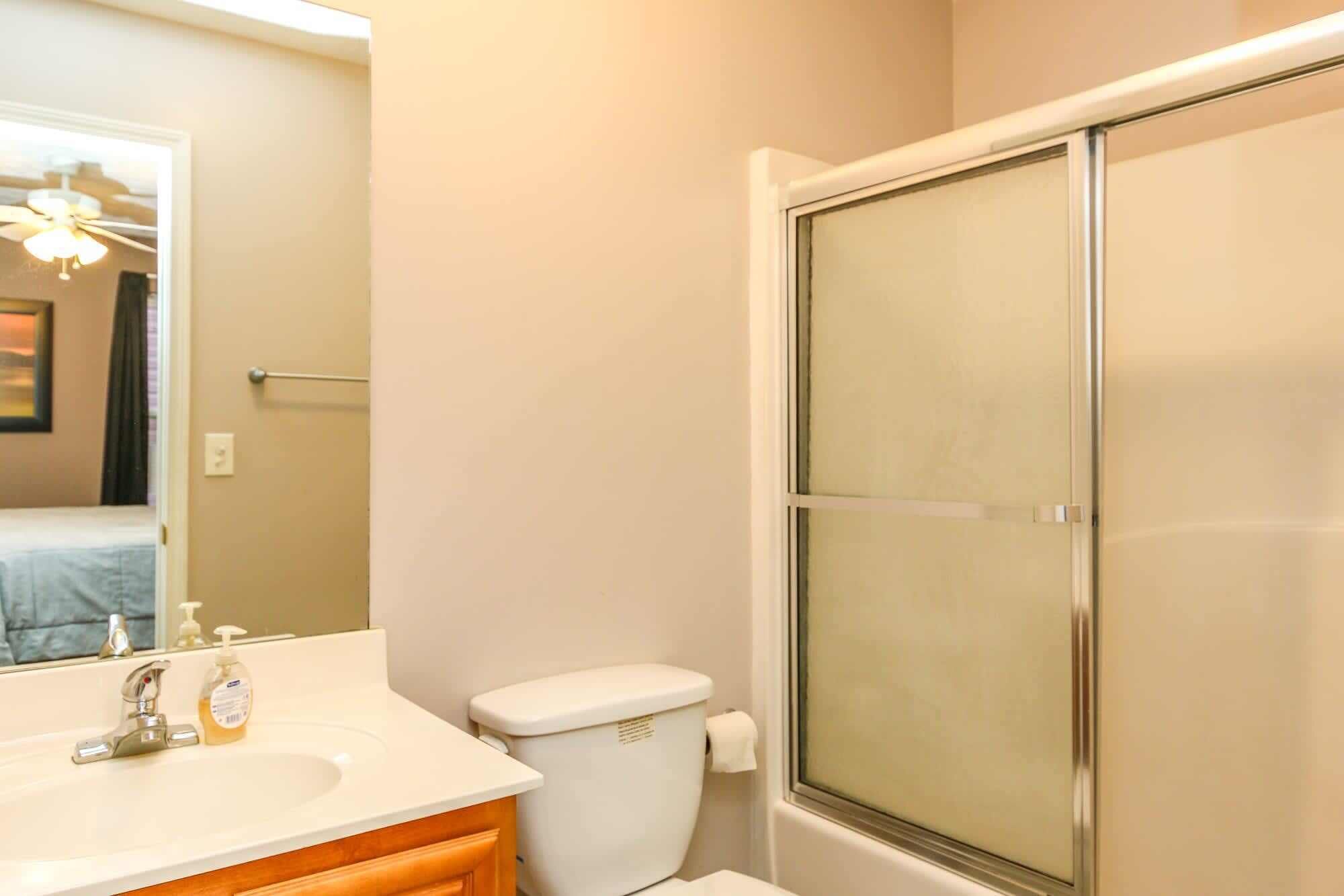 A bathroom with a sink, toilet, and a glass shower enclosure.