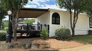 Une maison de plain-pied avec un porche couvert, un petit jardin agrémenté d’une haie et une allée pavée.