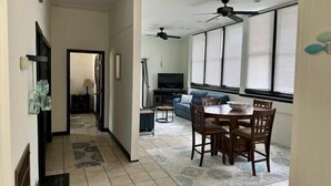 Un grand espace de vie comprenant une table et des chaises, un canapé, un téléviseur et un ventilateur de plafond.