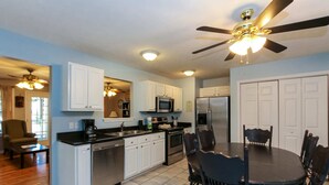 A modern kitchen with white cabinets, stainless steel appliances, and a dining area with a round table and chairs. - House #10 Paradise Found (pet friendly) private pier (Leesburg)