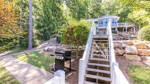 A house with a deck, a barbecue grill, and a wooden staircase leading to a porch. - House #10 Paradise Found (pet friendly) private pier (Leesburg)