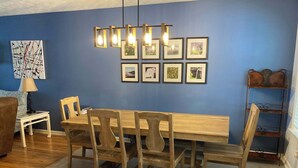 Een eethoek met een houten tafel en stoelen, een hanglamp en lijstwerken aan de muur.