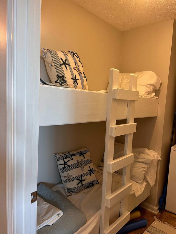 Una cama litera con dos niveles, cada uno con un cojín estampado con motivos de estrellas de mar.