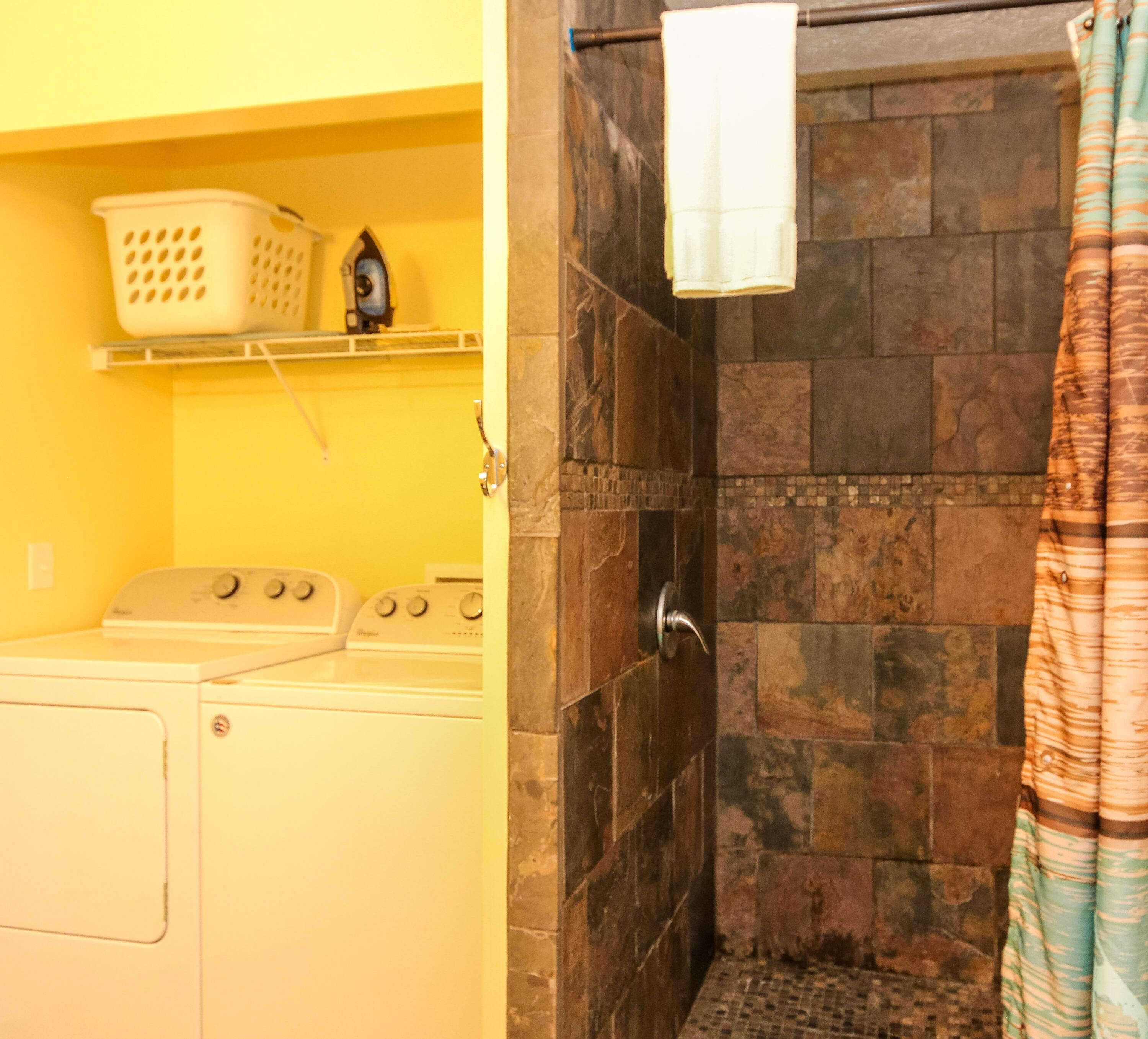 A laundry area with a washing machine, a dryer, and a hanging rack.
