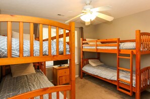 A room with two bunk beds, a desk, and a ceiling fan.