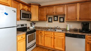 A kitchen with wooden cabinets, a refrigerator, a microwave, an oven, a dishwasher, a sink, and a coffee maker. - House# 30 Endless View Not Pet-Friendly (Leesburg)