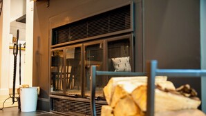 Un salon moderne avec une cheminée, une porte vitrée et une pile de bois de chauffage.