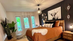 Une chambre à coucher avec un grand lit, une table de chevet en bois, une plante succulente et un luminaire au plafond.