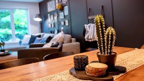 Un coin repas avec une table en bois, un chemin de table en dentelle, un cactus, une bougie et un sous-verre décoratif.
