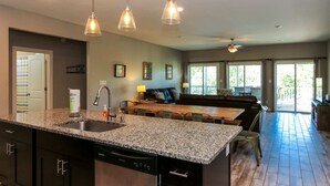 Une cuisine spacieuse dotée de plans de travail en granit, d’un lave-vaisselle et de luminaires suspendus.