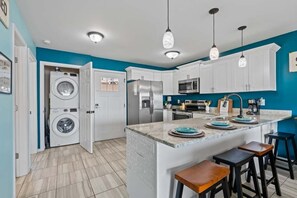 A compact kitchen with a built-in washer and dryer, a refrigerator, a microwave, and a sink with bar stools.