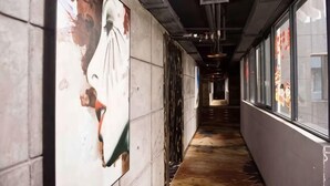 A corridor with a tiled floor, a wall with a large poster, and windows on the right side. - Zhangjiajie Mr.F Boutique Hotel (Tianmen Mountain Cableway Station) (Zhangjiajie)