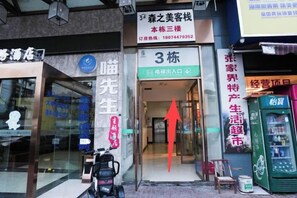 Fachada con un letrero que indica la entrada al tercer piso, una motocicleta estacionada afuera y una máquina expendedora a la derecha.