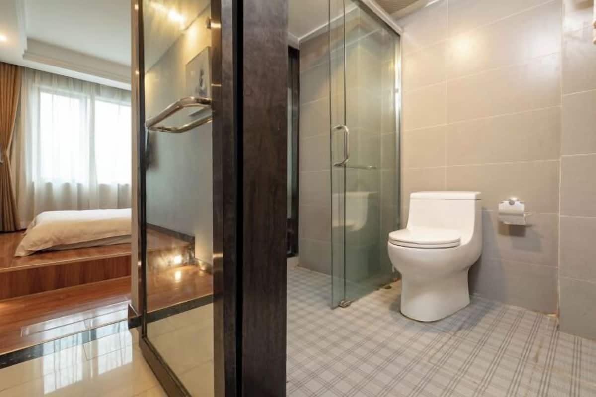 A modern bathroom with a glass shower enclosure, a white toilet, and a checkered floor.