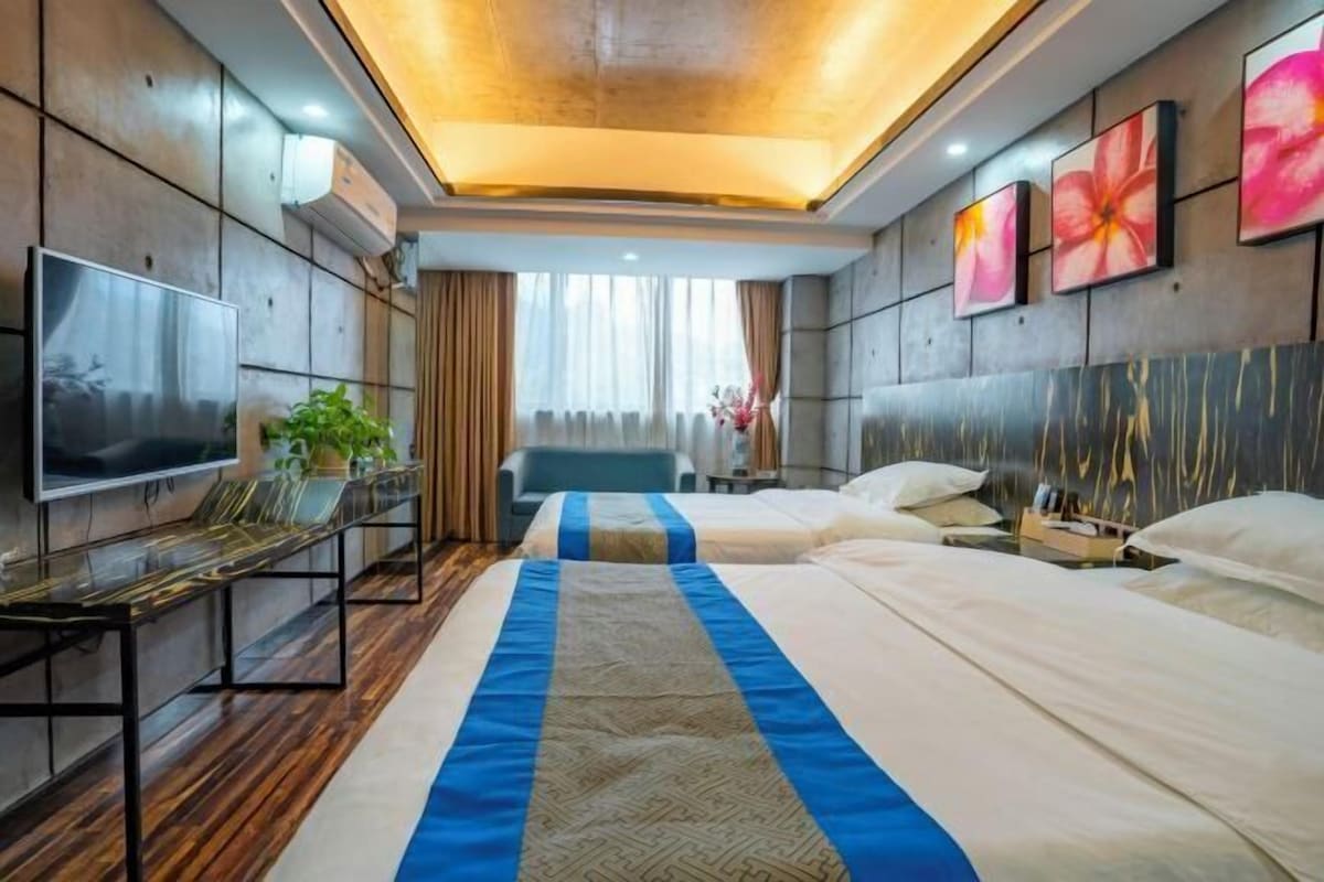 Une chambre d’hôtel avec deux lits, une télévision, un bureau et une vue sur l’extérieur.