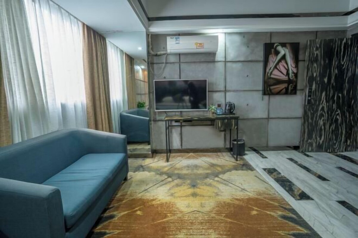 Un salon moderne avec un canapé bleu, un téléviseur, une table basse et un tapis à motifs.