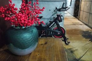 Una mesa de madera con un florero de bayas rojas, una bicicleta y una pared al fondo.