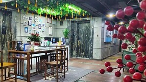 A reception area with a wooden desk, chairs, and a potted plant. - Zhangjiajie Mr.F Boutique Hotel (Tianmen Mountain Cableway Station) (Zhangjiajie)