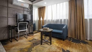 A modern hotel room with a sofa, a small table, a TV, and a desk with a chair. - Zhangjiajie Mr.F Boutique Hotel (Tianmen Mountain Cableway Station) (Zhangjiajie)