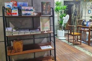 A reception area with a wooden floor, a reception desk, a plant, and a wall-mounted shelf with brochures and a sign. - Zhangjiajie Mr.F Boutique Hotel (Tianmen Mountain Cableway Station) (Zhangjiajie)