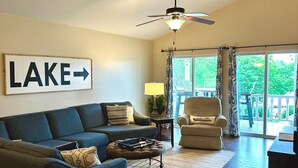 A spacious living room with a sofa, armchair, and a ceiling fan. A sign on the wall reads "LAKE" with an arrow pointing to the right. - House# 50 Home Away Home (No pets) (Leesburg)