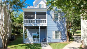 A two-story house with a front porch, a covered deck, and a small garden area.