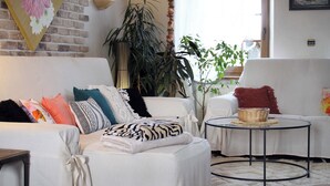 A modern living room with a white sofa, a round coffee table, and a large potted plant.