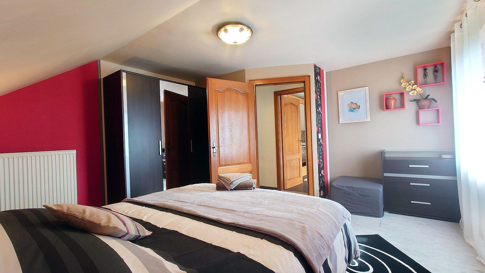 Un dormitorio con cama, armario, cómoda y espejo.