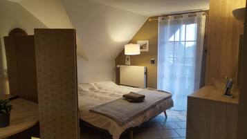 Une chambre à coucher avec un lit, une table de chevet, une lampe, un radiateur et une fenêtre avec des rideaux.
