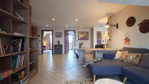A spacious living area with a sofa, a coffee table, and a bookshelf filled with books.
