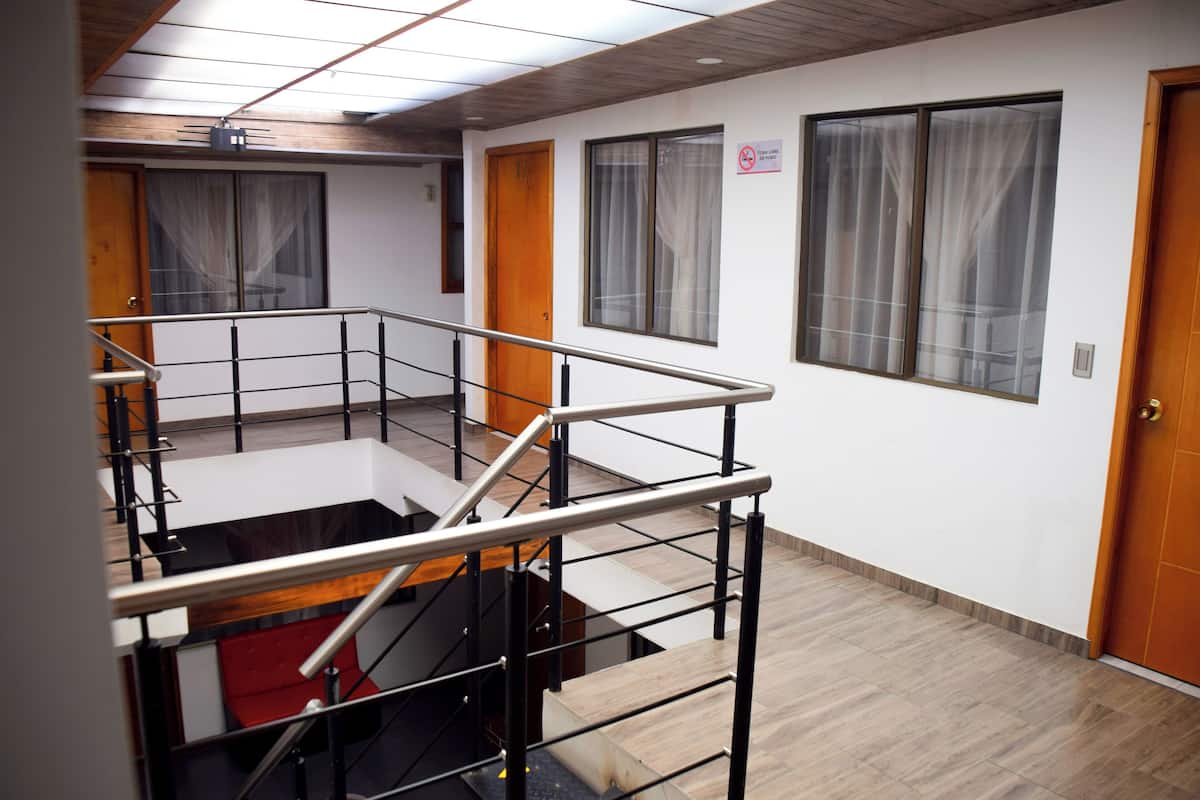 A hotel interior with a staircase, wooden flooring, and a view of the outside through large windows.