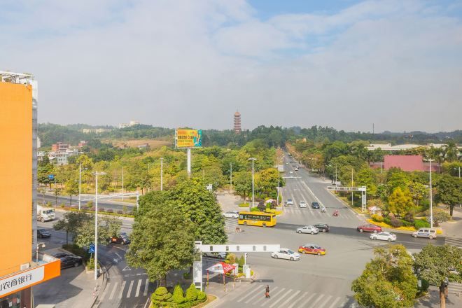 A wide street with multiple lanes, trees, and buildings in the background.