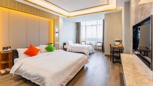 Habitación de hotel con dos camas, televisión, escritorio y ventana.