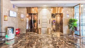 Un moderno vestíbulo de hotel con suelo de mármol, una recepción, una máquina expendedora y una planta.