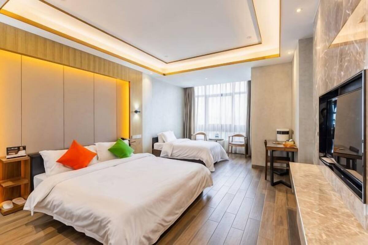 Habitación de hotel con dos camas, televisión, escritorio y un ventanal grande.