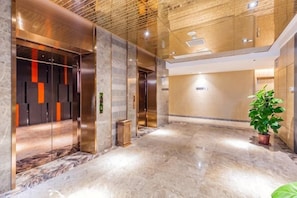 A modern lobby with marble flooring, elevators, and a potted plant. - Rimei Hotel (Foshan Sanshui New Power) (Foshan)